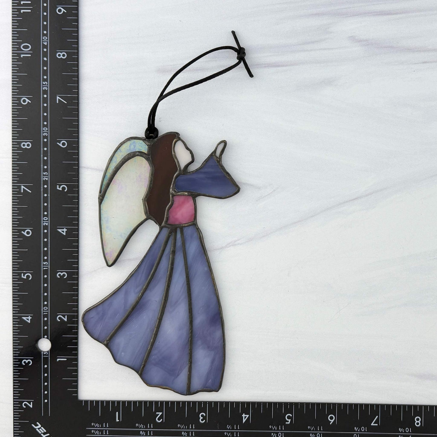 Stained glass angel ornament with a ruler for scale on a white background