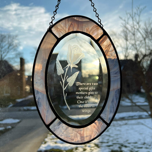 This stained glass beveled oval suncatcher with an etched rose is a perfect gift for any mother. The clear oval bevel measures 8x6 inches and is surrounded by an inch of multicolored pink glass. It would be a thoughtful gift for a new mom, as a symbol of the journey they are embarking on with their child. 