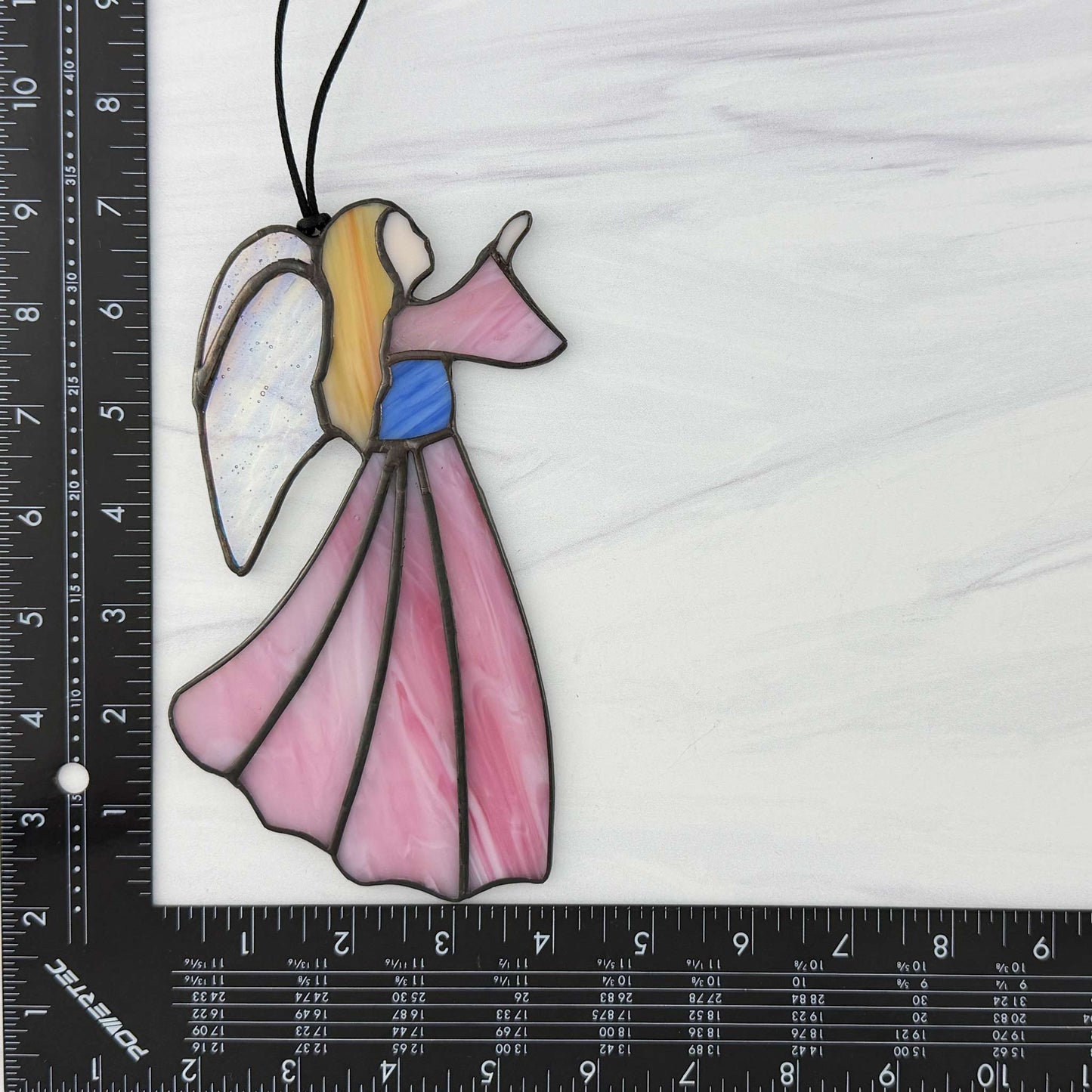 Pink stained glass angel suncatcher with a ruler for scale on a white background