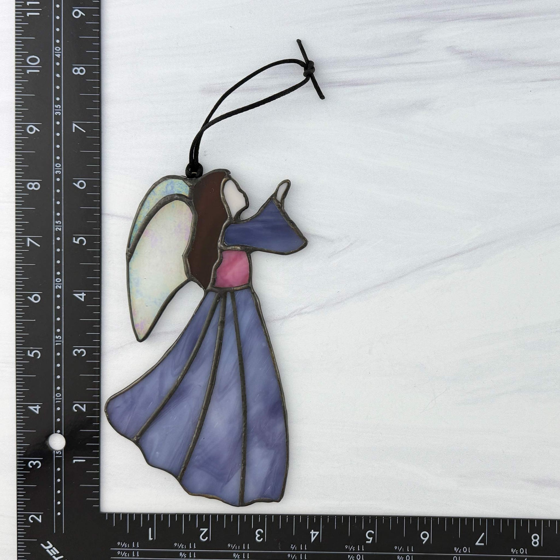 Stained glass angel ornament with a ruler for scale on a white background