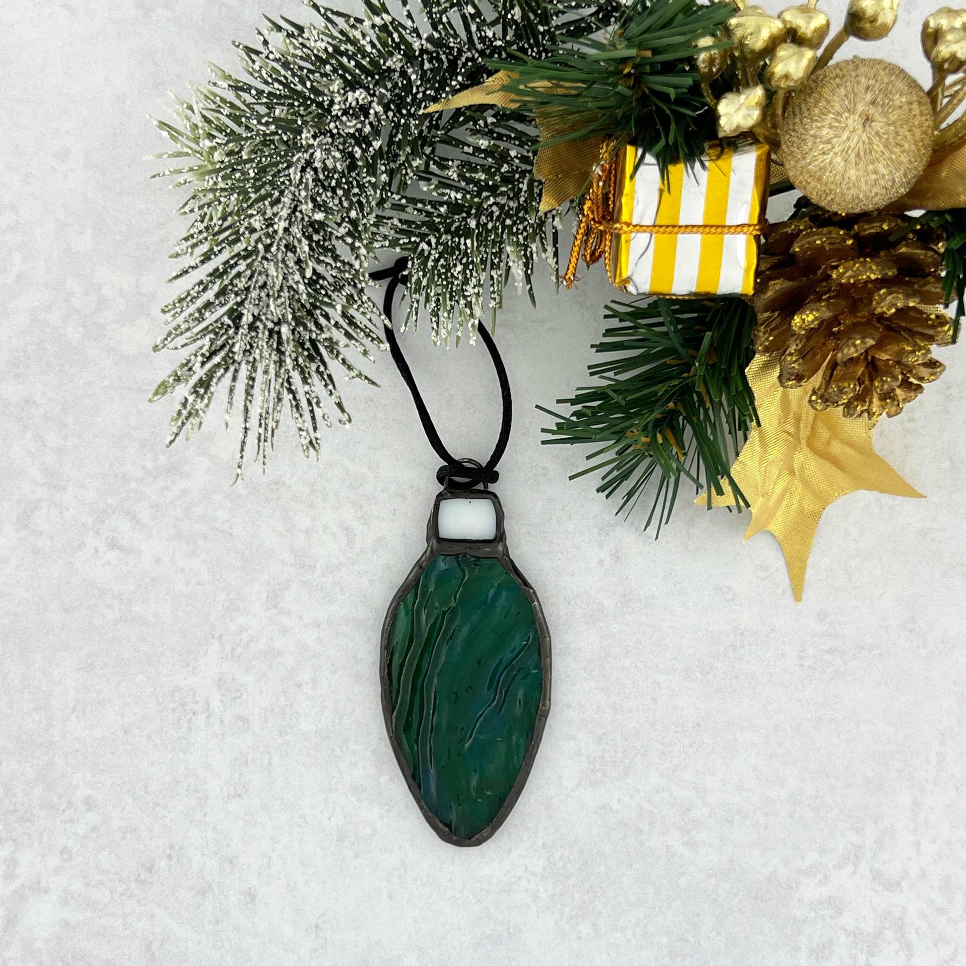 Green-Blue rippled stained glass bulb shaped Christmas ornament hung from a black cord.