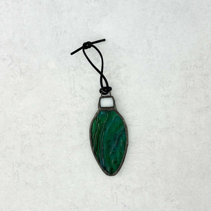 Green-Blue rippled stained glass bulb shaped Christmas ornament hung from a black cord shown on a white background.