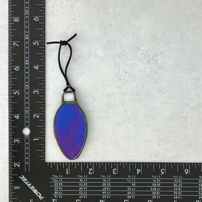 Iridescent Teal-Blue stained glass bulb shaped Christmas ornament shown with a ruler for size reference
