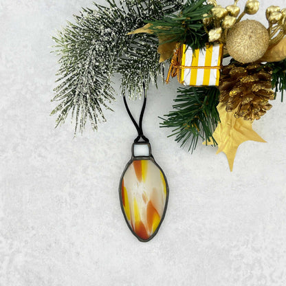 Decorative yellow-orange-white and clear stained glass bulb shapped ornament on a black string.