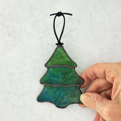 Hand holding a blue-green stained glass Christmas Tree made with a ripple textured glass