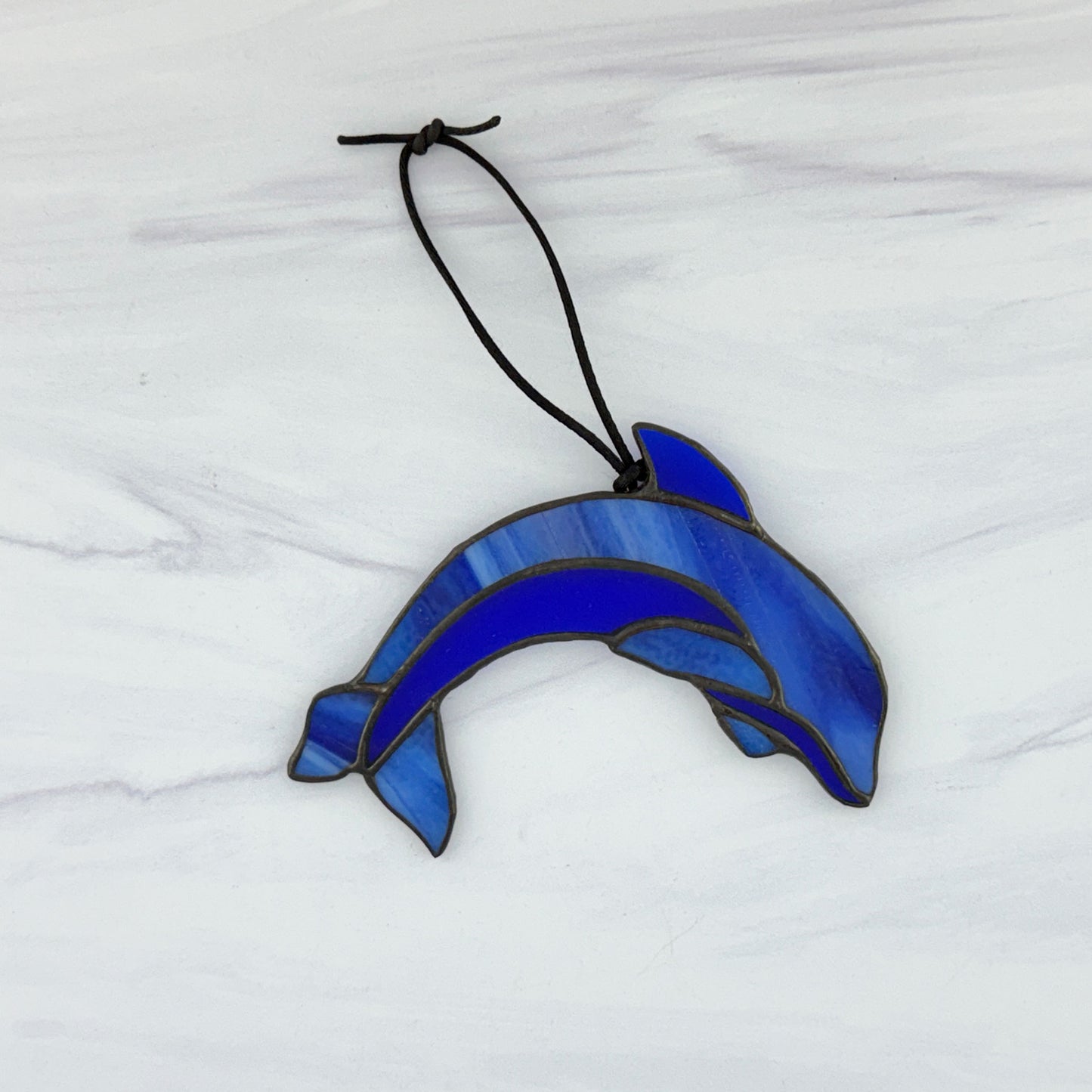 Blue stained glass dolphin stained glass suncatcher on a white marble background