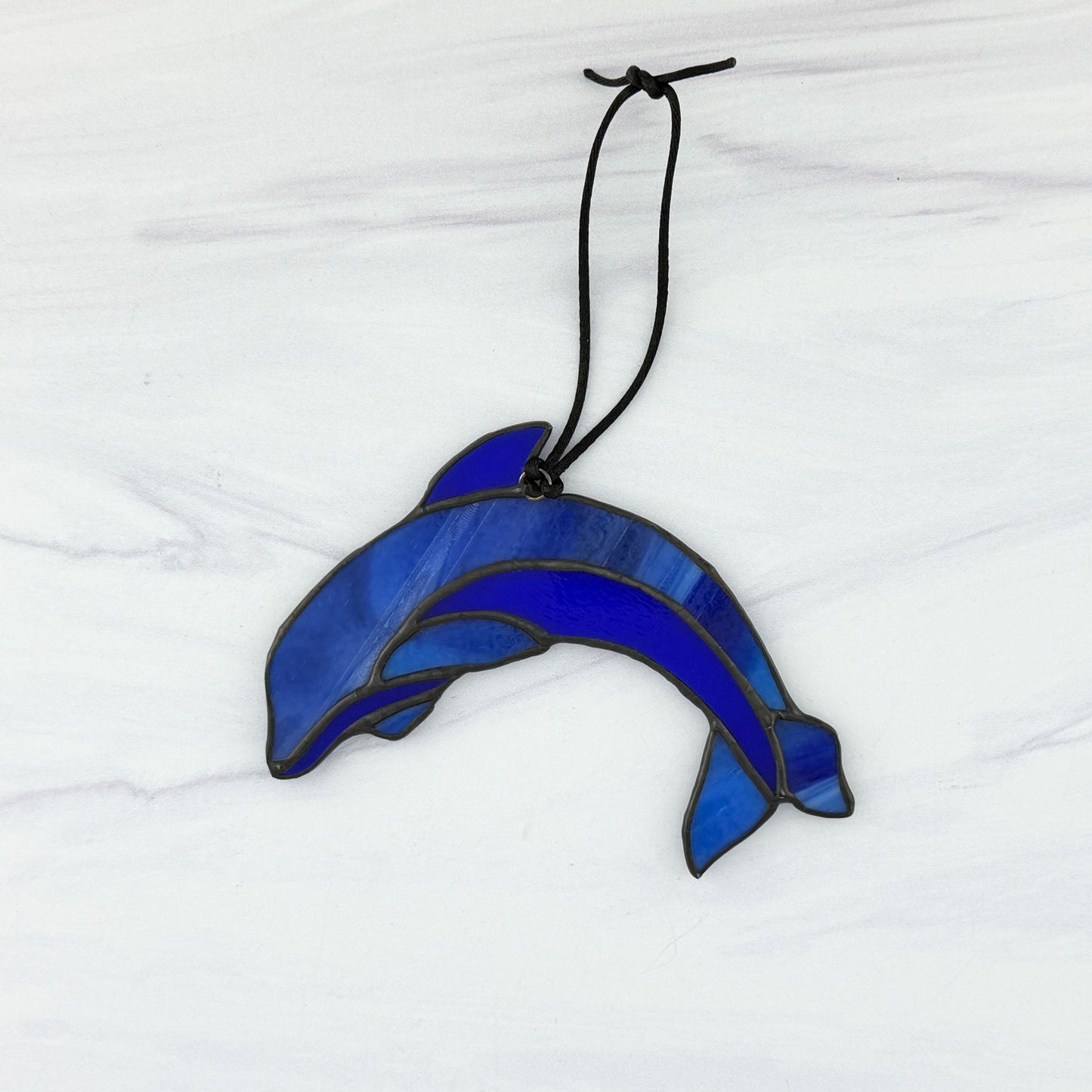 Blue stained glass dolphin ornament on a white background. View of the back side