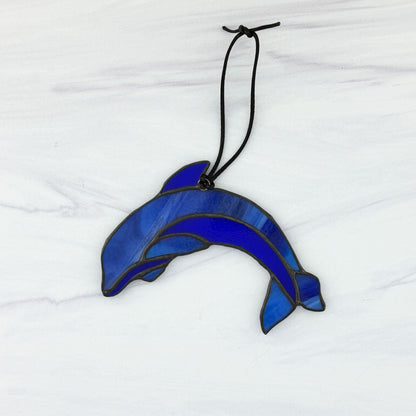 Blue stained glass dolphin ornament on a white background. View of the back side