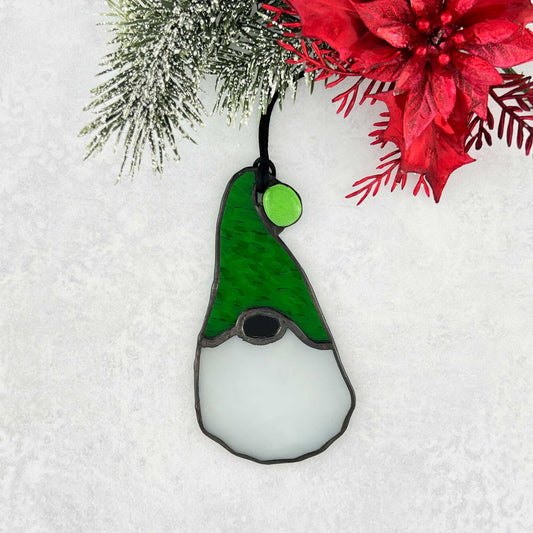 Stained glass gnome ornament with green hat on a snowy background