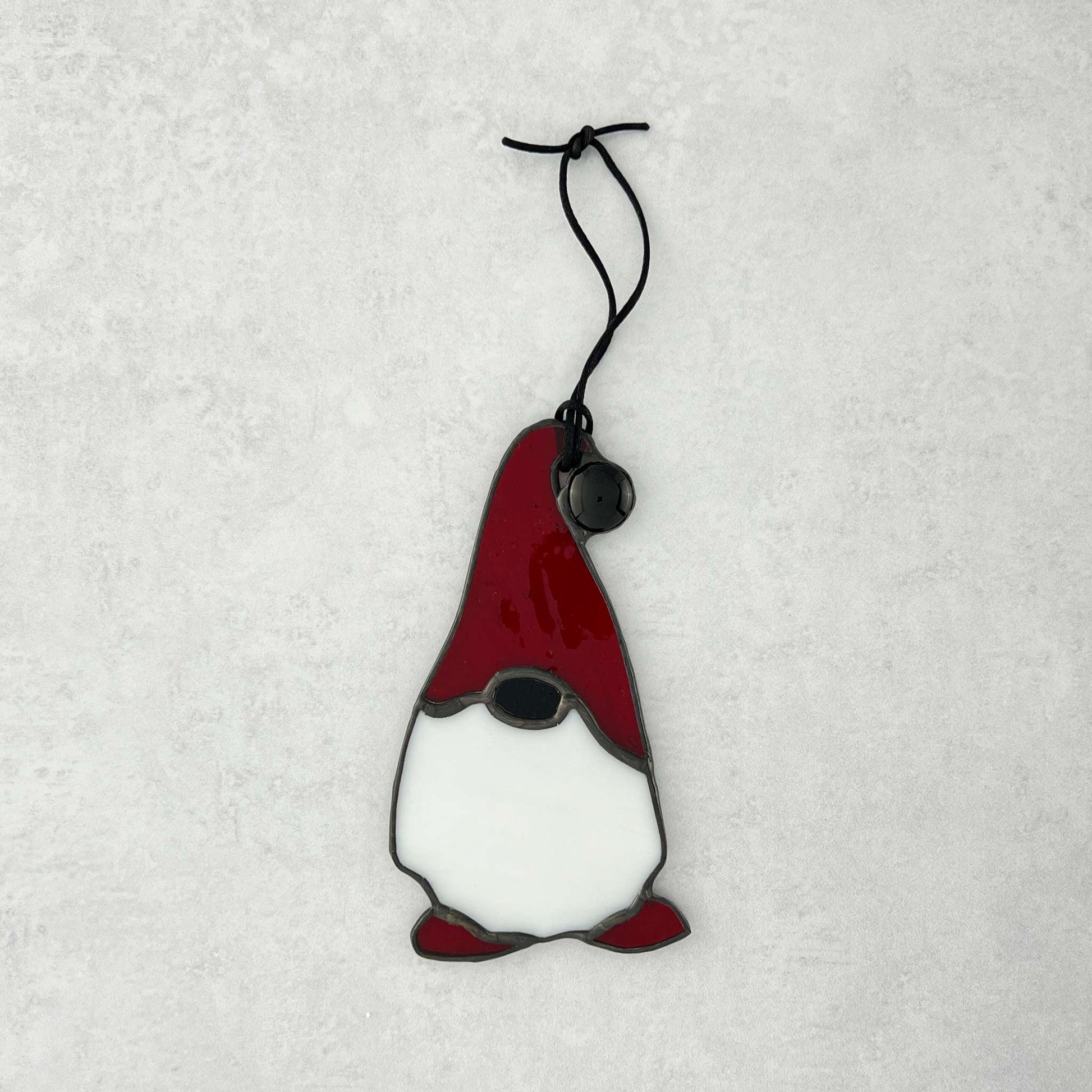 Stained glass gnome ornament with a red hat on a white background