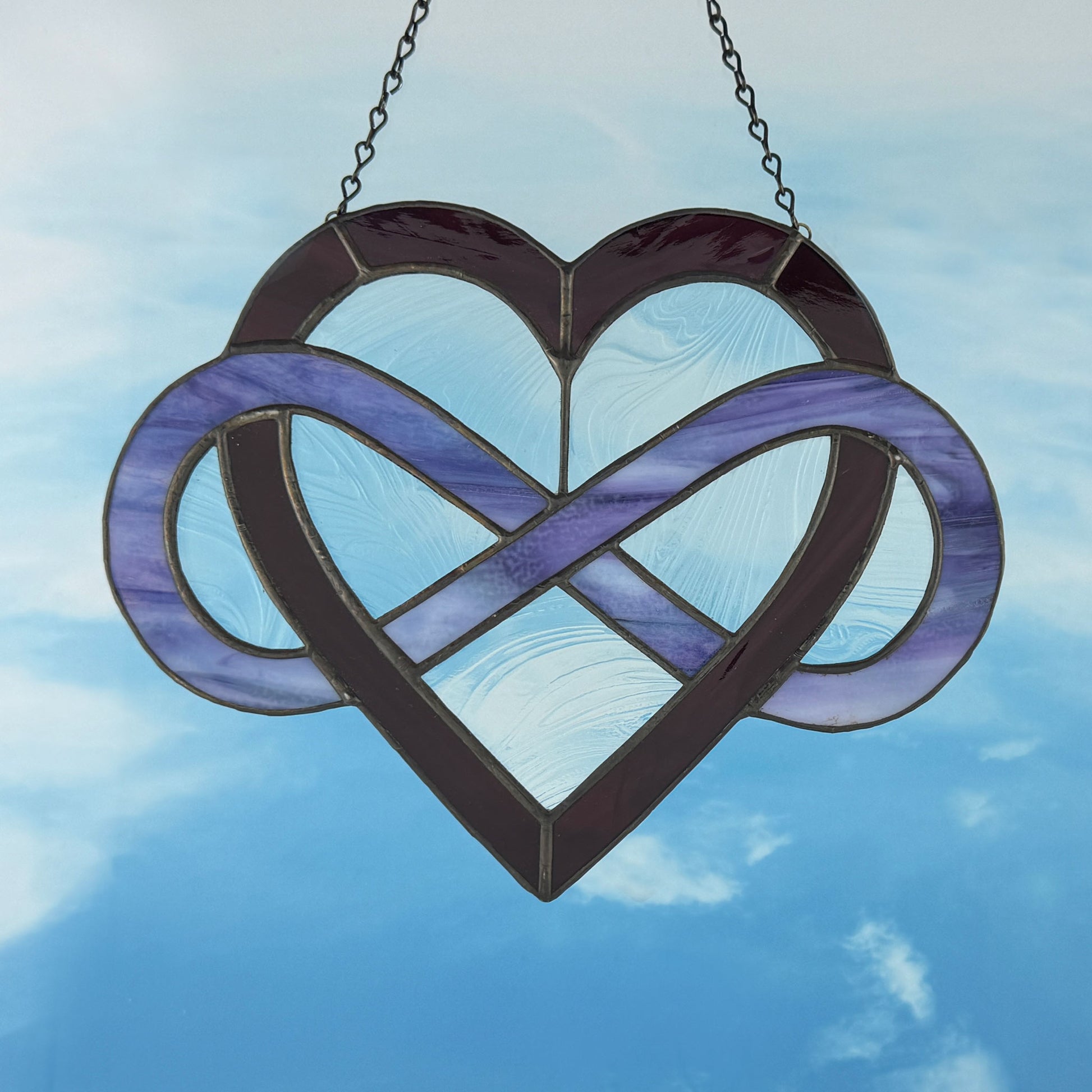 Purple Infinity Heart stained glass suncatcher hanging against a blue sky