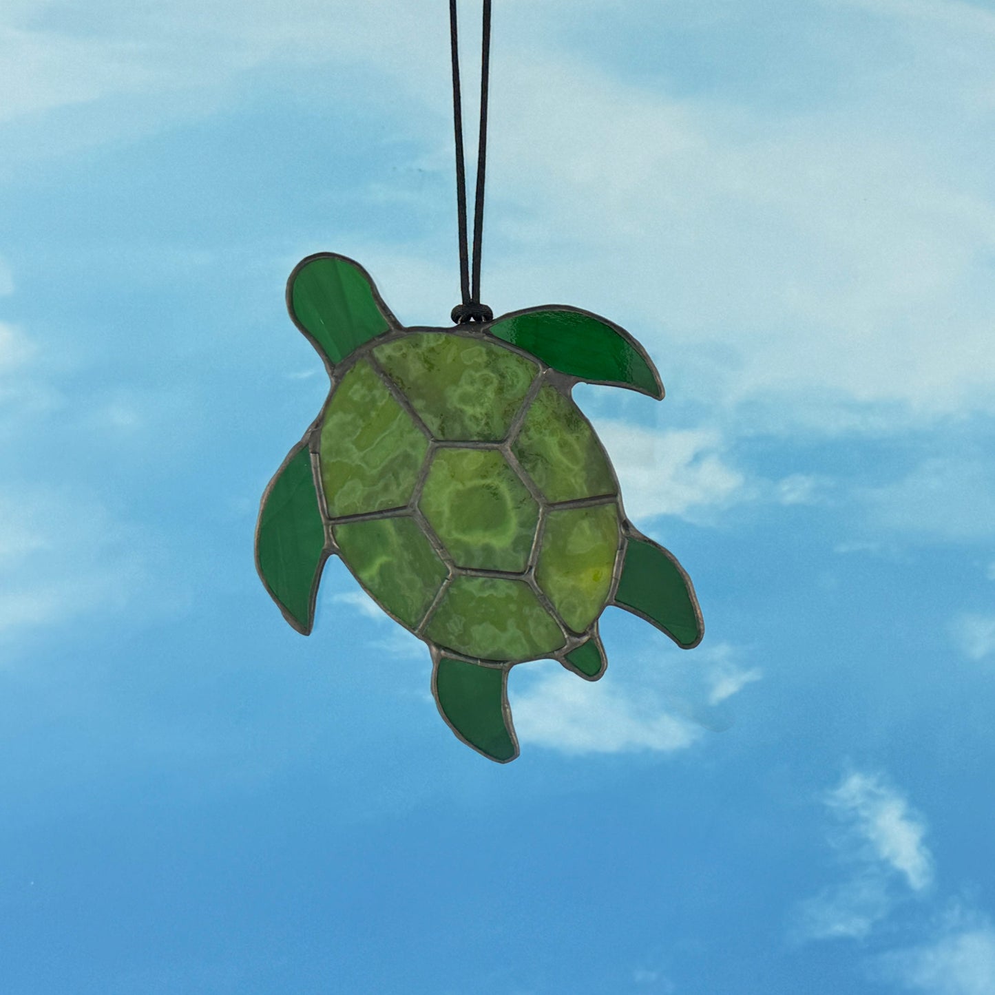 Green turtle ornament against a blue sky