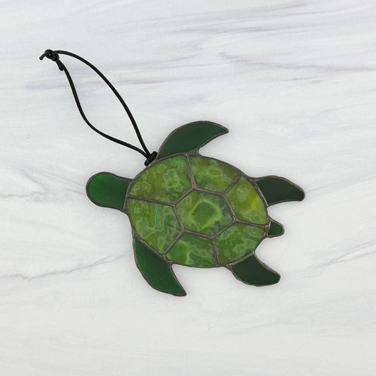 Green stained glass sea turtle ornament on a white background. The shell is mottled green with dark green flippers and head
