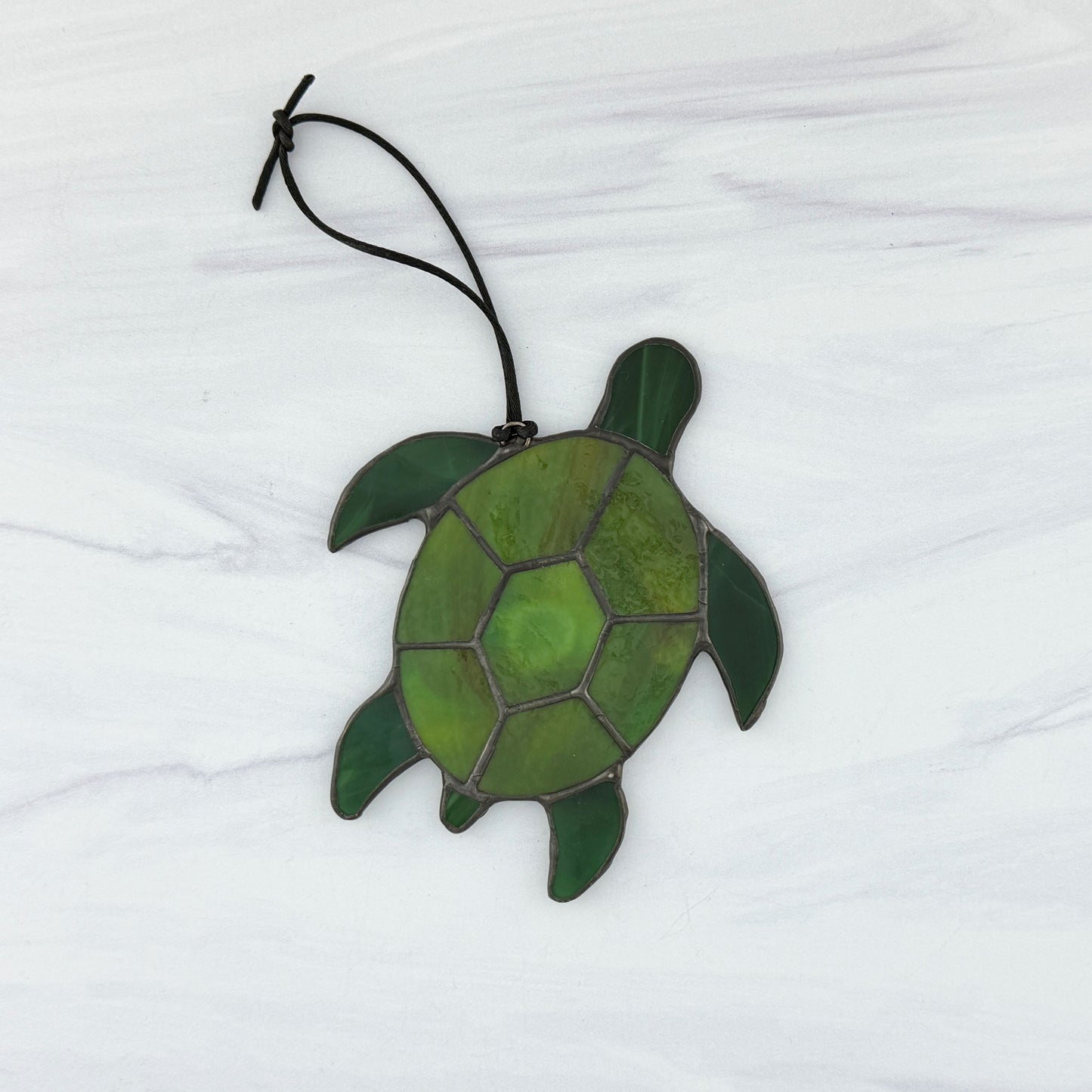 The back side of a Green stained glass turtle ornament on a white background
