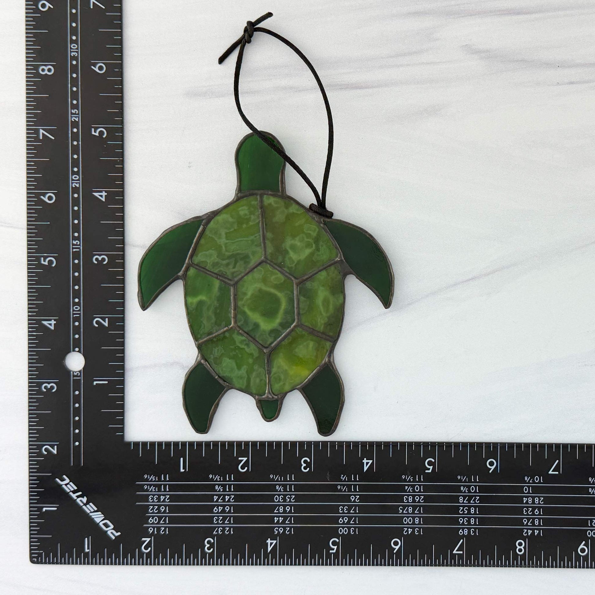 Green sea turtle suncatcher on a white background with a ruler for scale.