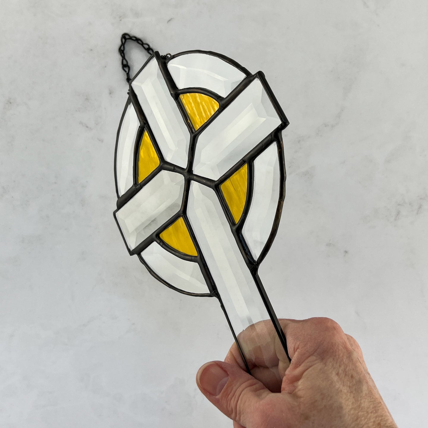 Clear beveled stained glass cross with yellow highlights around the arms of the cross  enclosed by  a clear bevel circle.  It is 9 inches by 6 inches and makes a great Easter gift for your religious friends.