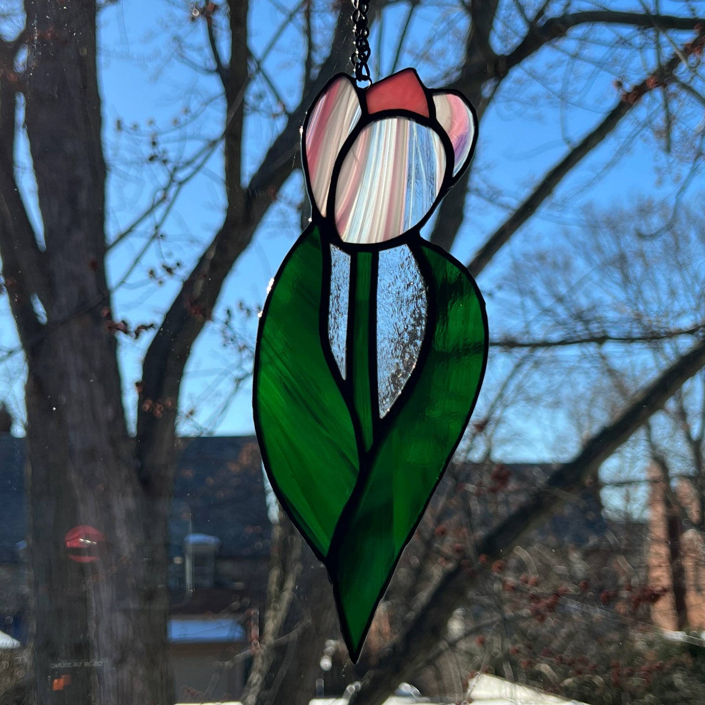 This tulip suncatcher captures the essence of spring! It is made with pink “Baroque” glass and features two green leaves. It is 7.5x3 inches and makes the perfect gift for your loved ones, especially for those who love nature and flowers. It's an excellent choice for Mother's Day, Easter, birthdays, or any occasion.